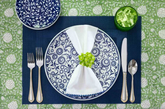 Blue and white floral dinner plate with a white napkin, green flower napkin ring, navy placemat and green glass on a spring tablescape.