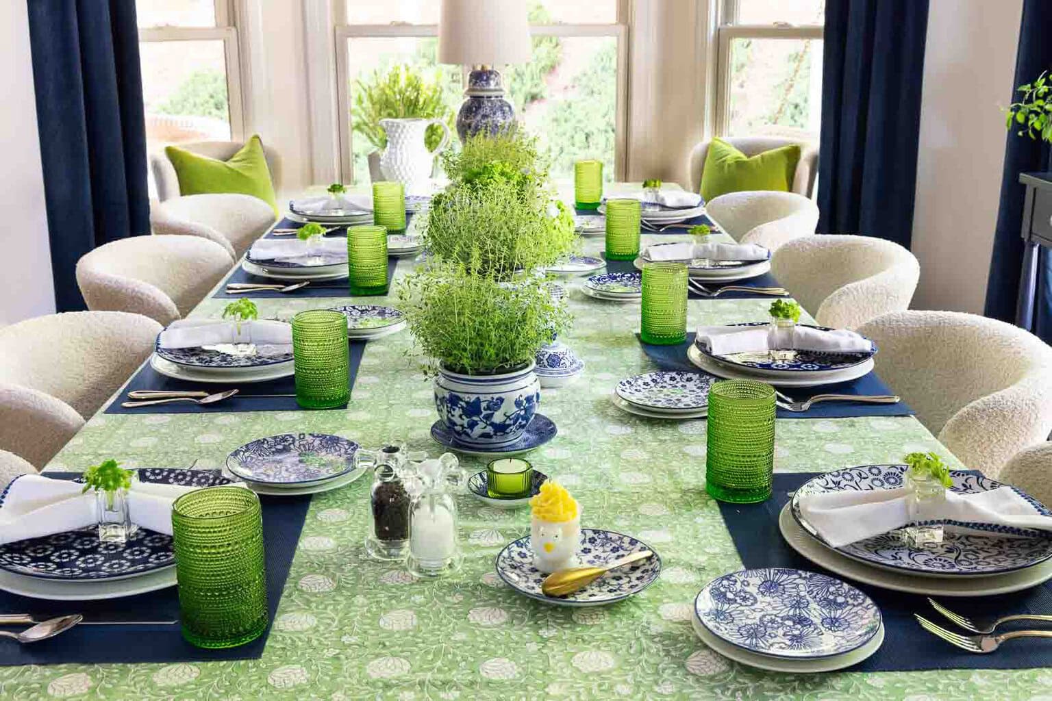 Blue and green spring-summer tablescape with navy and white dishes, herb centerpieces in ginger jars, green glassware and elegant entertaining details.