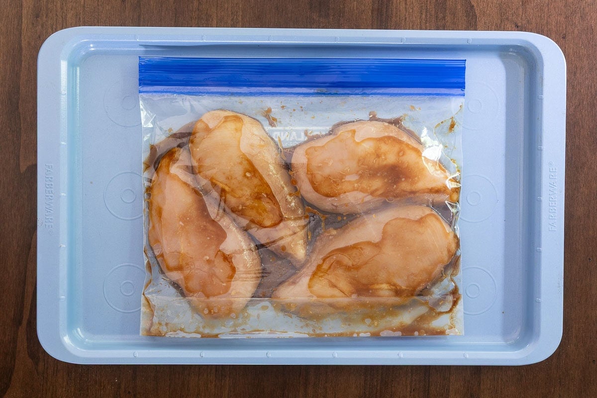 Chicken breasts marinating in a balsamic vinegar, olive oil and garlic marinade in a zip-top bag.