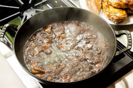 Balsamic rosemary pan sauce simmering with mushrooms in a cast iron skillet for One-Pan Balsamic Rosemary Chicken.