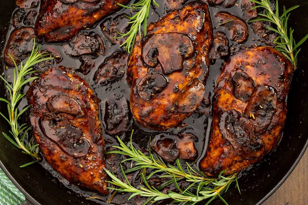 Close-up of One-Pan Balsamic Rosemary Chicken with mushrooms in a rich balsamic rosemary pan sauce, garnished with fresh rosemary.