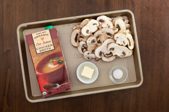 Sliced crimini mushrooms, chicken broth, butter and kosher salt for the mushroom topping in One-Pan Balsamic Rosemary Chicken.