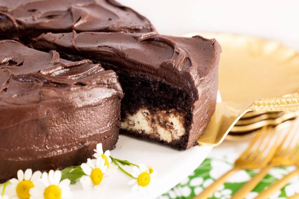 Marry Me Italian Love Cake with a slice removed, showing the chocolate cake and creamy ricotta layers beneath chocolate frosting.