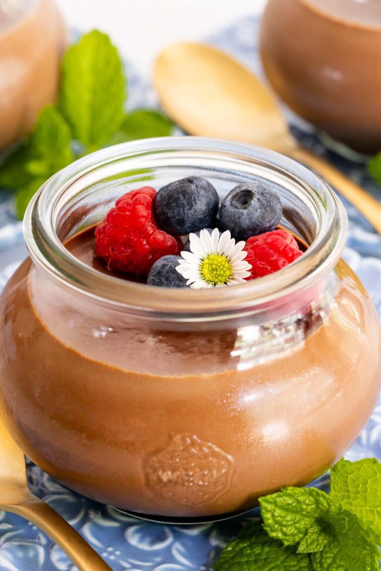 Ridiculously Easy Chocolate Panna Cotta in a small glass jar with berries and a flower.
