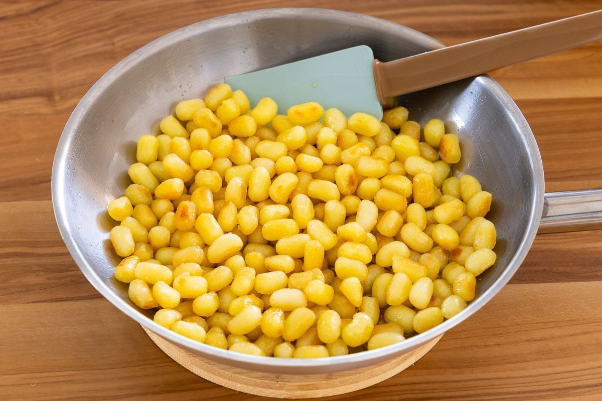 Mini gnocchi cooking in a skillet until golden brown and crispy for crispy gnocchi salad.