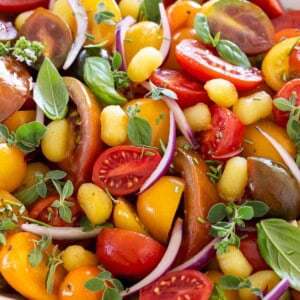 Crispy gnocchi salad with colorful heirloom tomatoes, cherry tomatoes, fresh basil, oregano, red onion, and herbs.