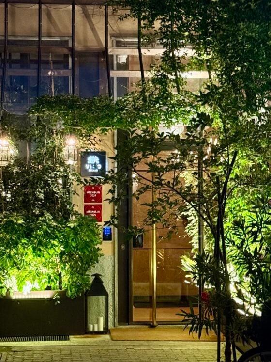 Lush courtyard entrance to Vico Milano, an elegant boutique hotel/restaurant in Milan, Italy, illuminated with greenery and evening lights.