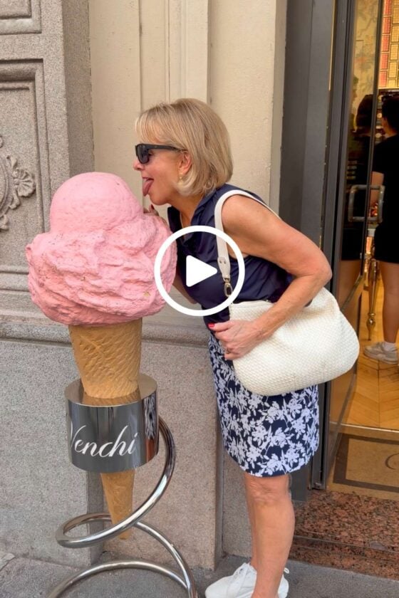 Chris playfully pretending to lick a giant pink gelato cone display outside a gelateria in Milan, Italy.