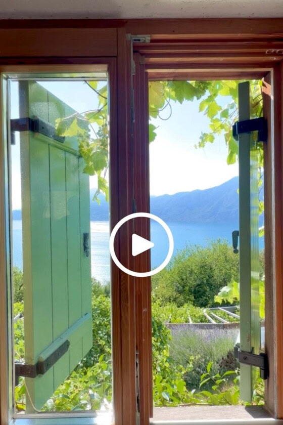 Open kitchen window overlooking Lake Garda with vineyard vines, herb gardens, and mountain views at Hildegard's home in Italy.