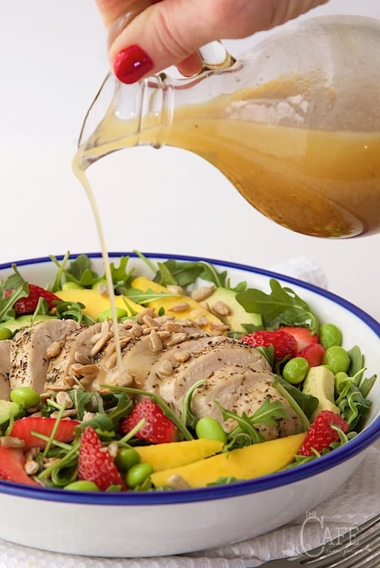 Image of pouring dressing over Arugula Chicken Salad with Honey Lime Dressing.