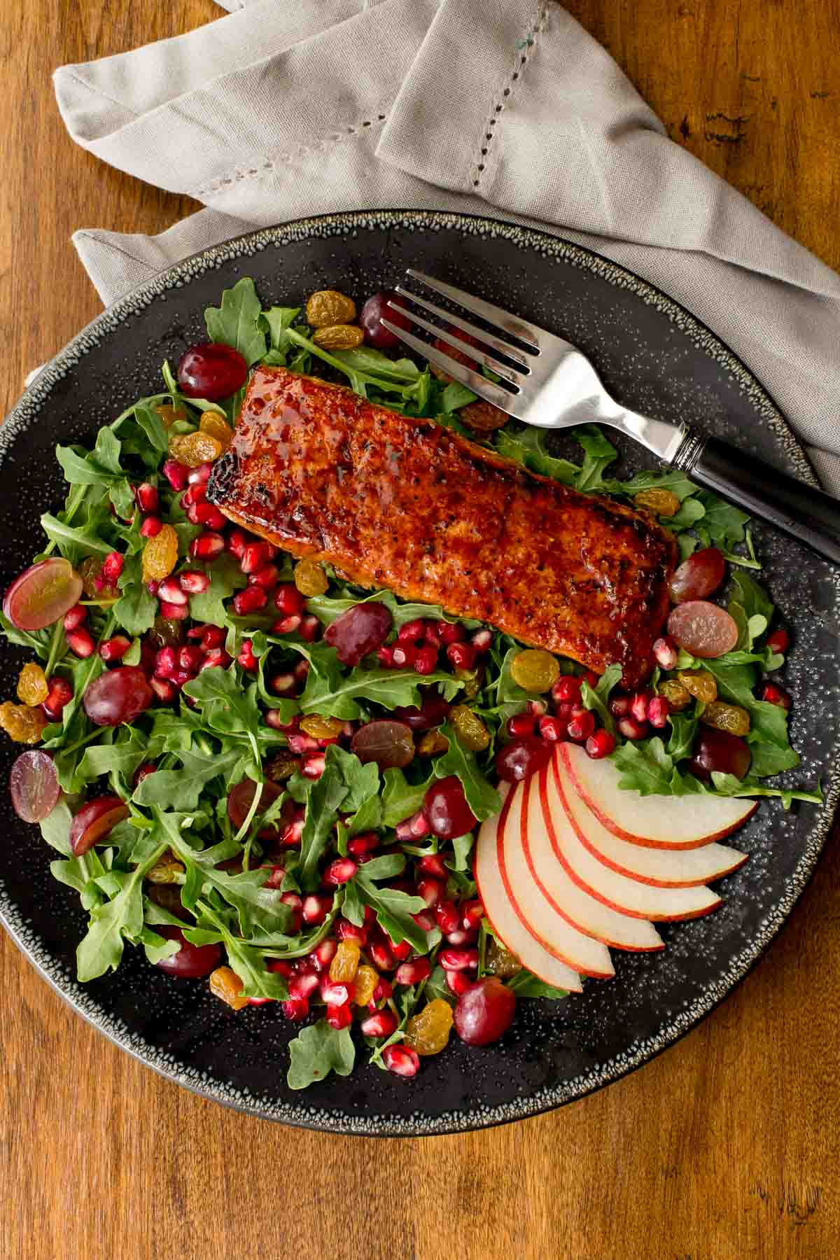 Overhead vertical photo of Asian Glazed Salmon Salad in a black serving plate on a wood table.