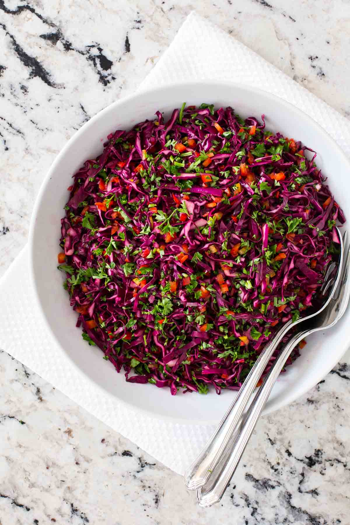 Overhead vertical photo of Asian Red Cabbage Slaw in a white serving bowl on a granite countertop.