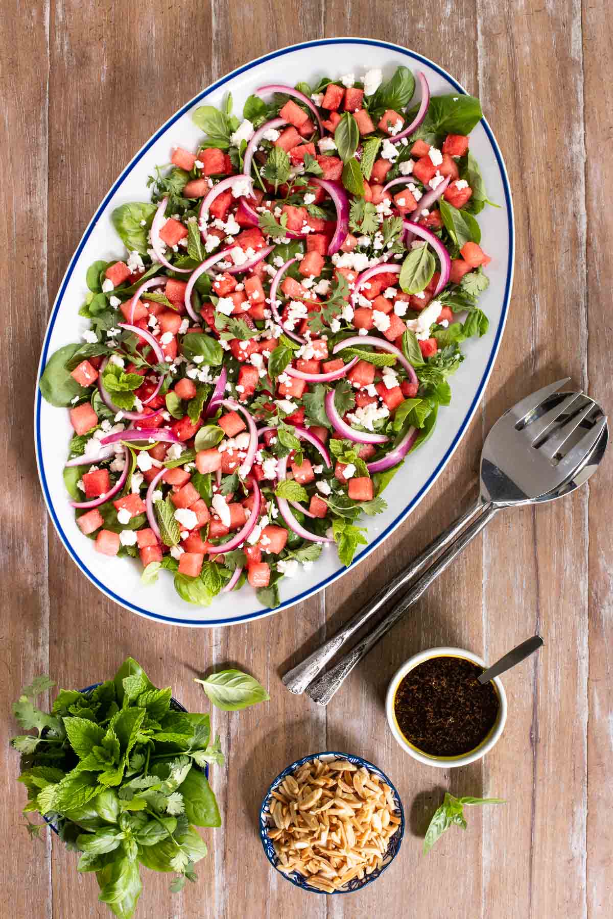 Vertical overhead photo of an Asian Watermelon Herb Salad on a wood dining table.