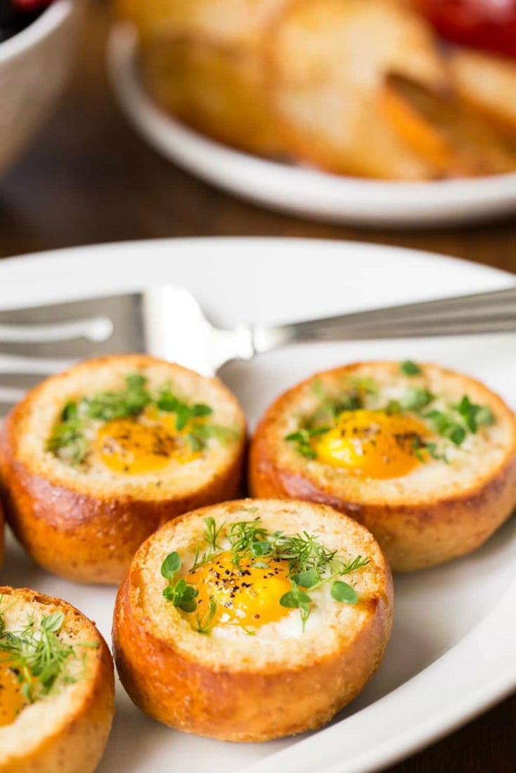 Close up photo of Baked Eggs in Bread Baskets on a white platter.