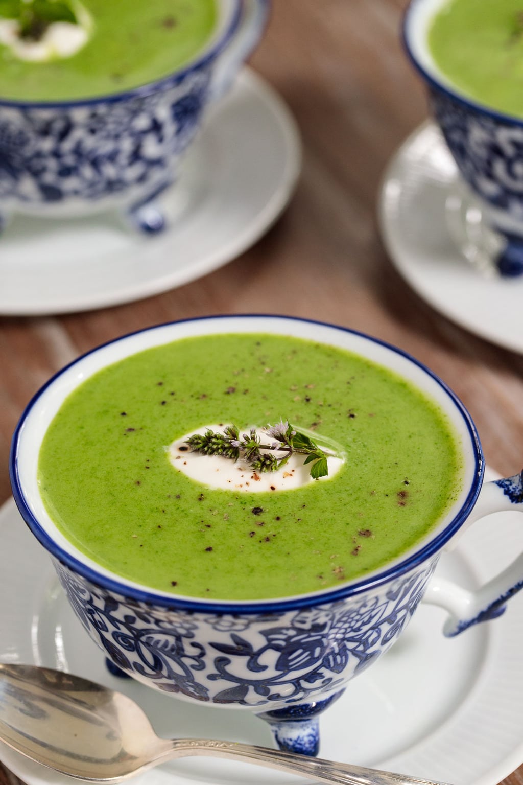 Vertical picture of spinach soup in a blue and white mug