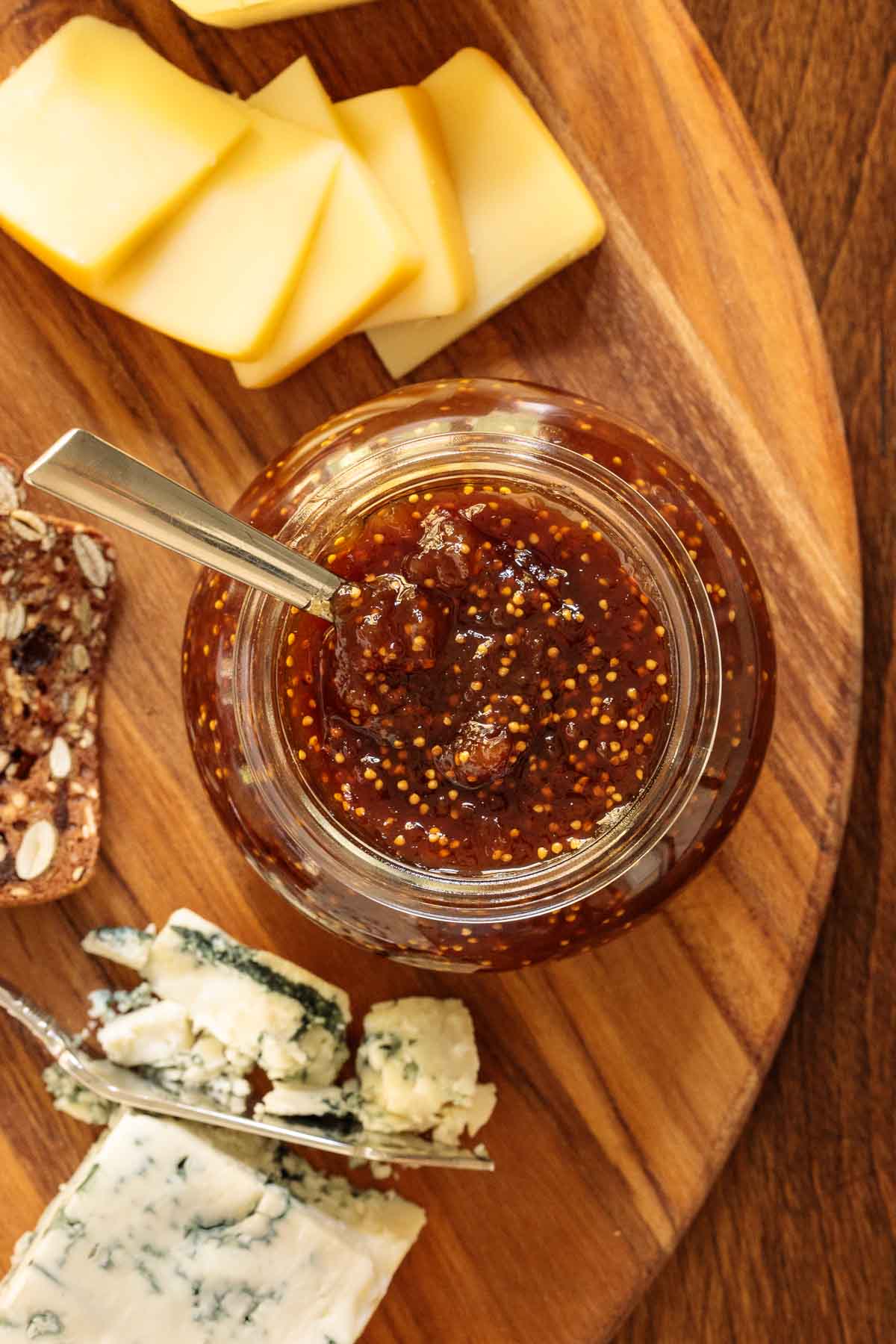 Overhead vertical closeup photo of Easy Balsamic Fig Jam on a wooden cutting board with cheese and crackers.