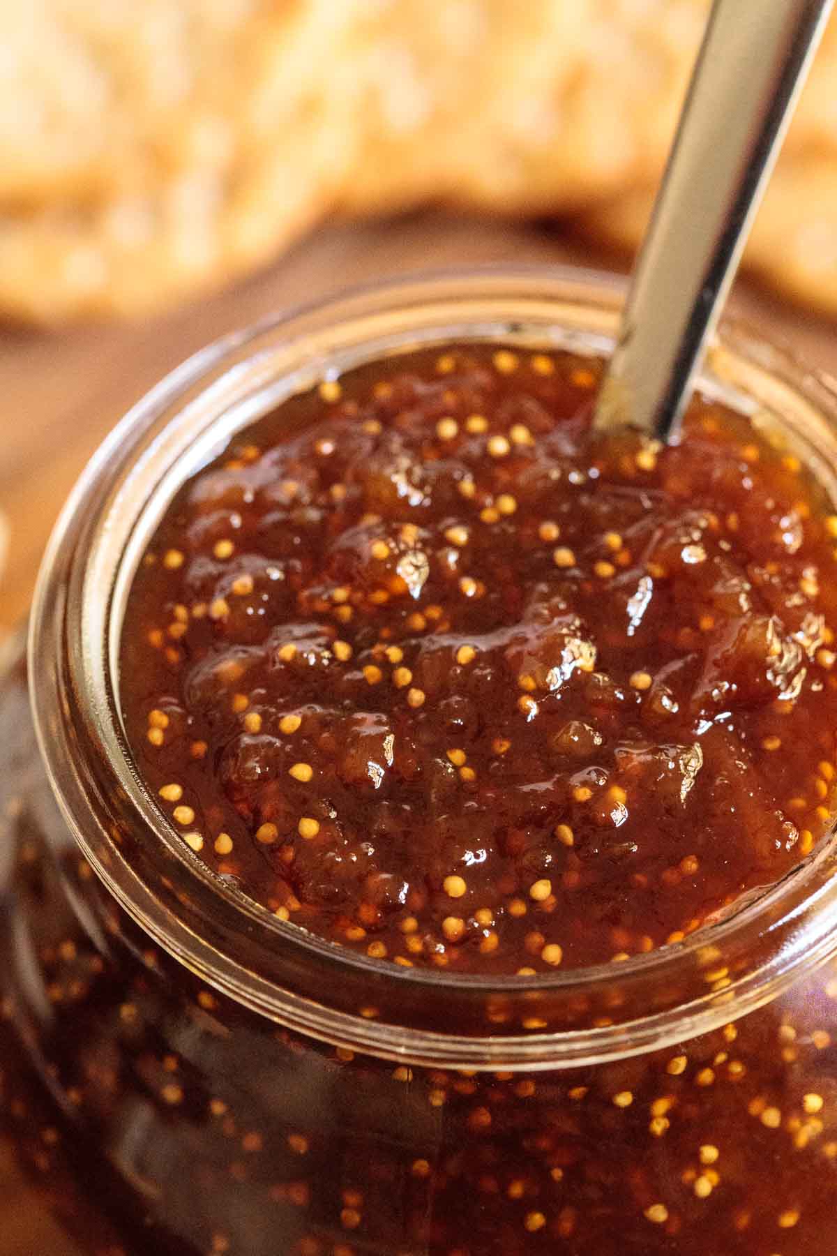 Closeup photo of a jar ofEasy Balsamic Fig Jam with appetizer crackers in the background.