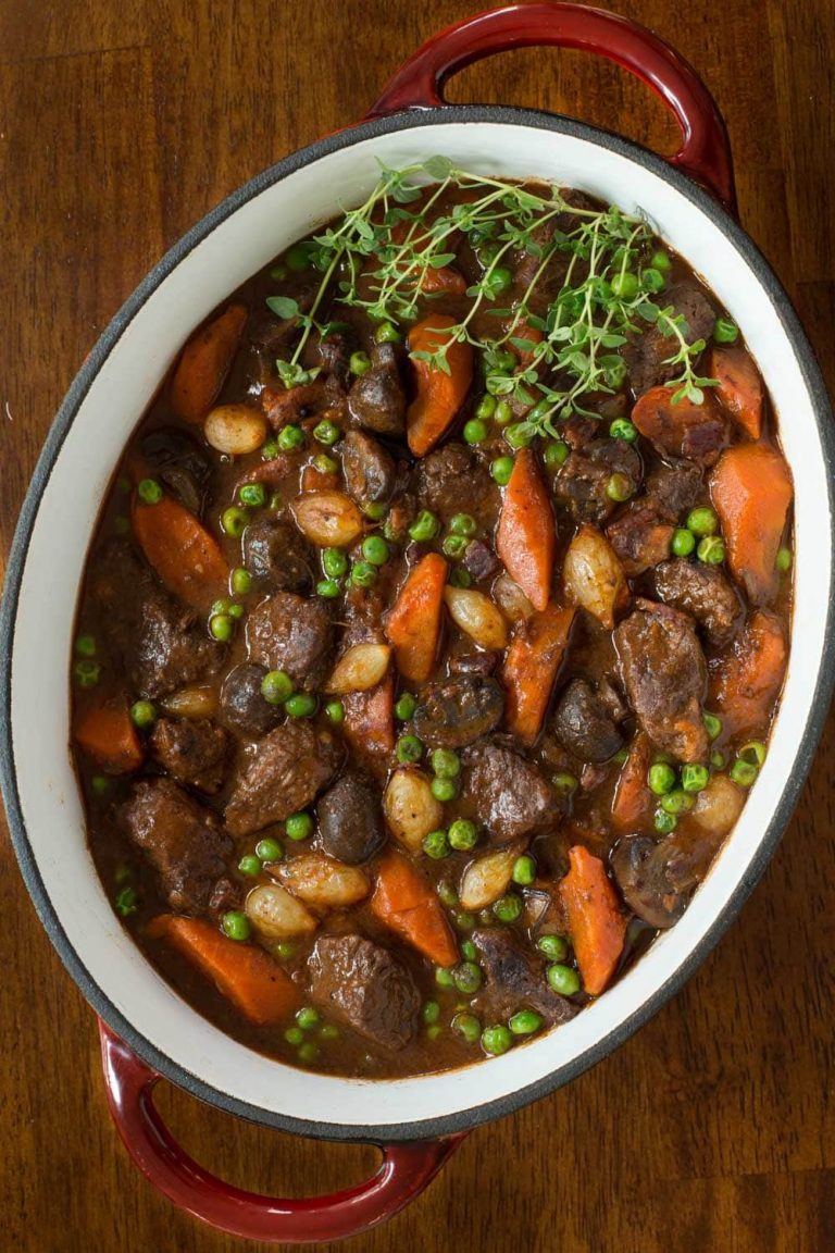 Overhead picture of beef bourguignon in an oval pot on a wooden table