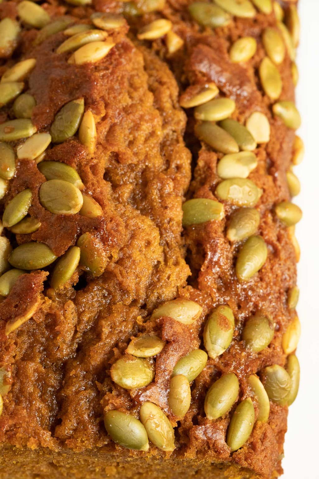 Extreme closeup vertical photo of the top of a loaf of Better Than Starbucks Pumpkin Bread (One-Bowl, No-Mixer!) featuring the pumpkin seed top crust.