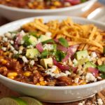 Vertical picture of black bean beef and tortilla soup in white bowls loaded with toppings