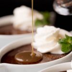 Vertical picture of Blender Chocolate Pots de Crème in small white dishes with creme sauce poured on top