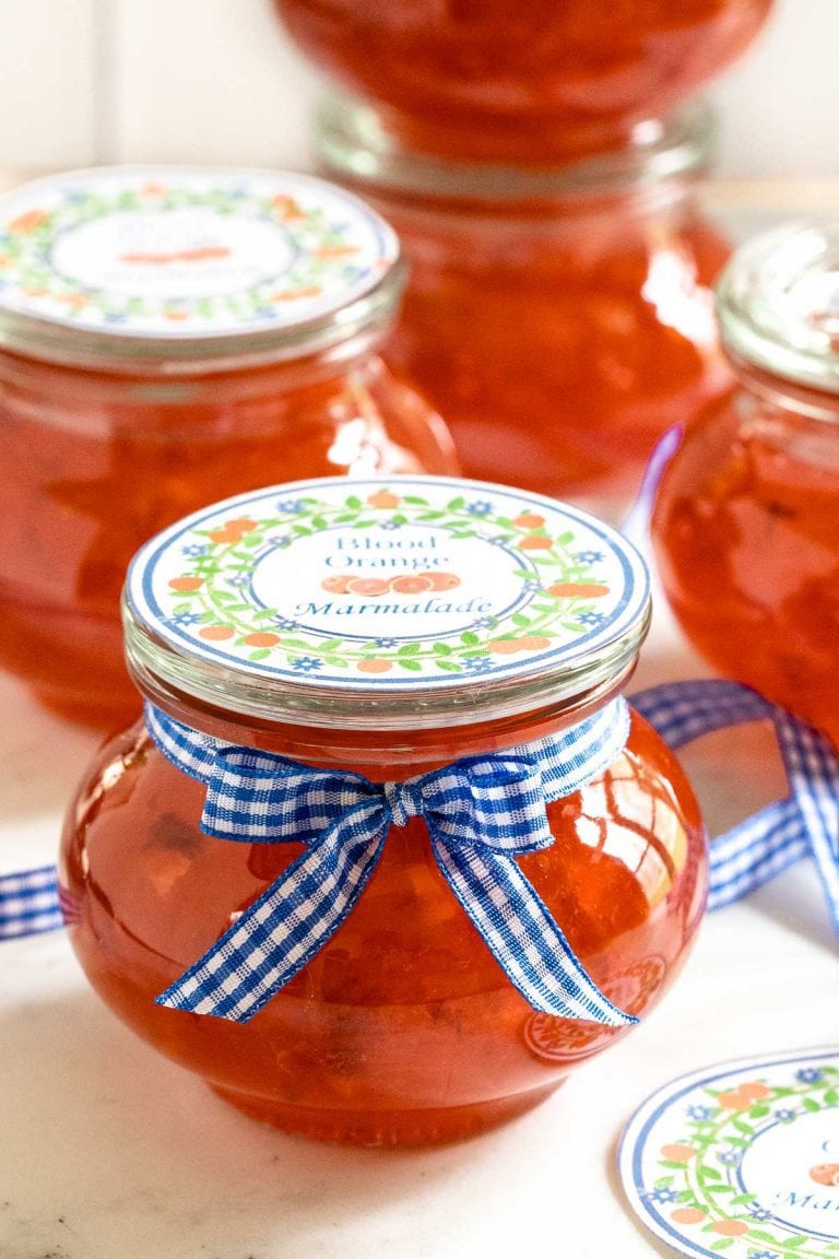 Vertical picture of blood orange marmalade in small glass jars with labels and ribbon