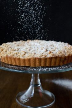 Vertical Image of falling powdered sugar on Blueberry Crumb Cake.