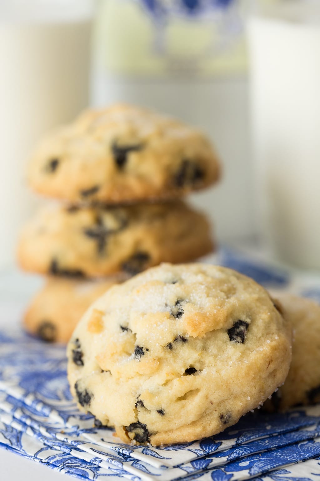 Vertical photo of Lemon Blueberry Shortbread Cookies stacked on blue and white patterned napkins.