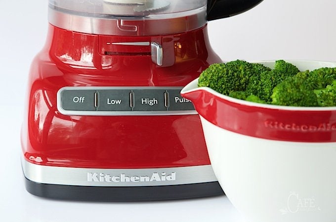 Close up picture of broccoli and a red food processor