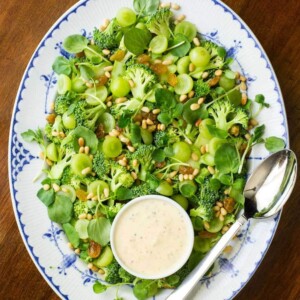 Vertical overhead view of entire Broccoli Salad with Grapes and Watercress on a blue and white platter.