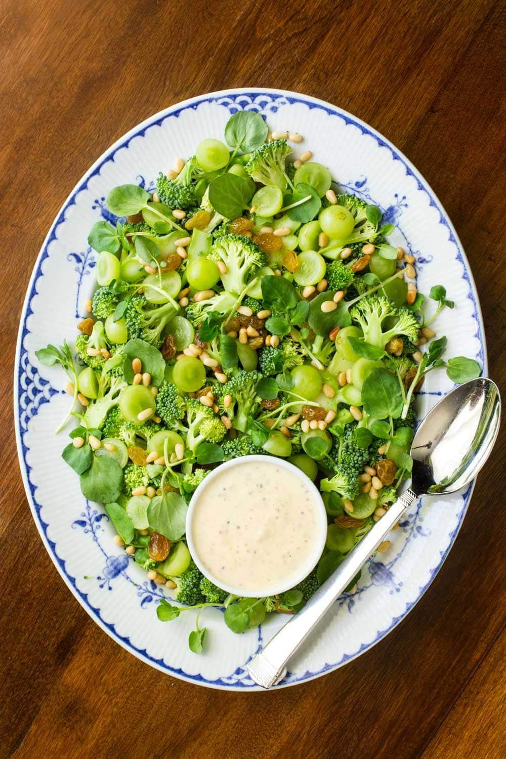 Vertical overhead photo of an entire Broccoli Salad with Grapes and Watercress on a blue and white platter.