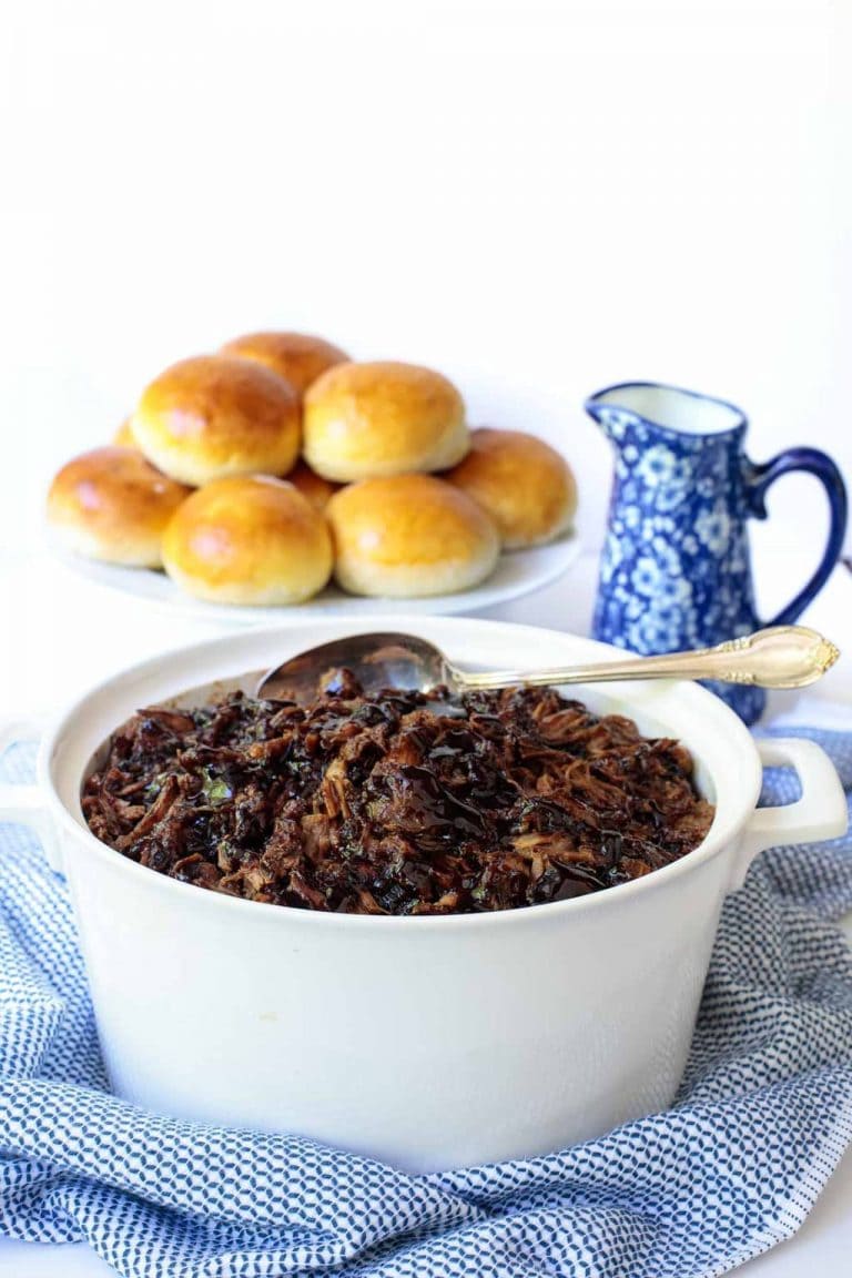 Vertical picture of Brown Sugar Balsamic Pulled Pork in a white pot with buns in the background