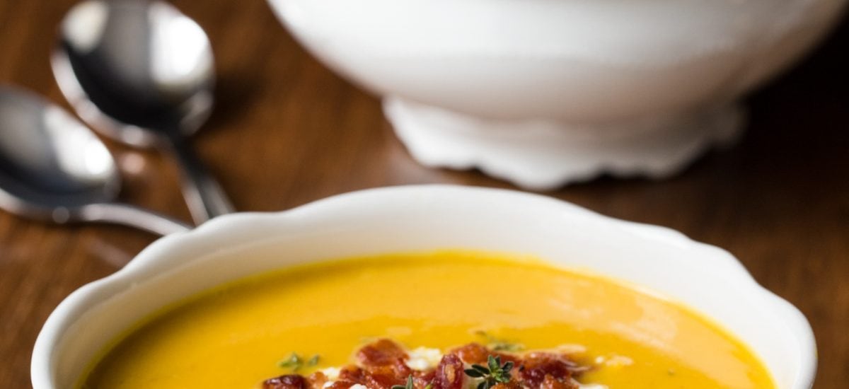 Vertical picture of Butternut Squash and Bacon Soup in white bowls on a wooden table
