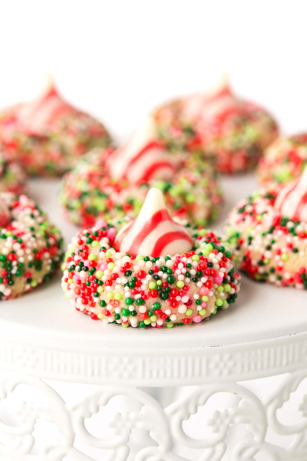 Vertical close up picture of candy cane shortbread cookies on a white cake stand