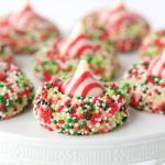 Candy Cane Shortbread Cookies - easy, whimsical and eye-catching, these incredibly delicious cookies have a buttery shortbread base and a sprinkle coating, topped with a Hershey's candy-cane kiss.