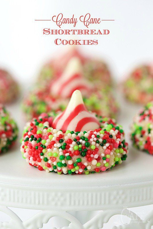 Candy Cane Shortbread Cookies - easy, whimsical and eye-catching, these incredibly delicious cookies have a buttery shortbread base and a sprinkle coating, topped with a Hershey's candy-cane kiss.