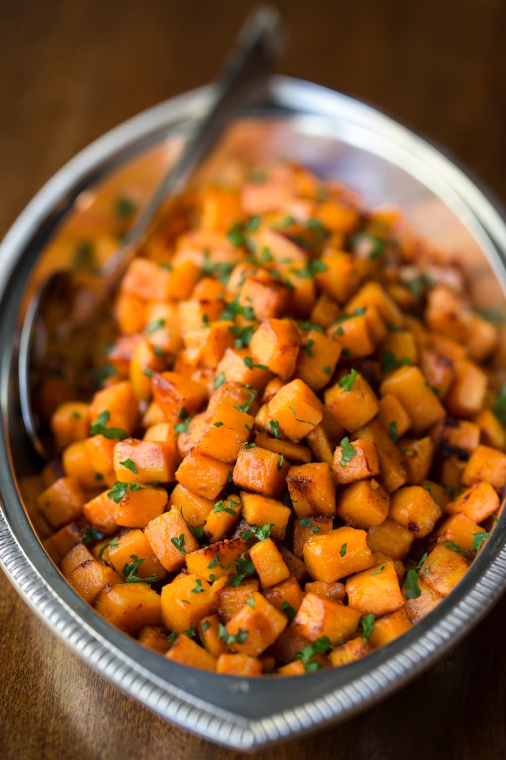 Vertical close up photo of Caramelized Sweet Potatoes in a silver presentation platter.