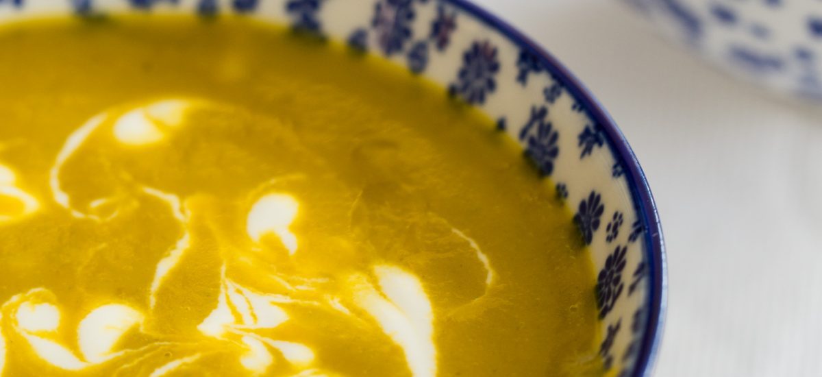 Vertical closeup photo of Carrot Coriander Soup in blue and white patterned serving bowls.