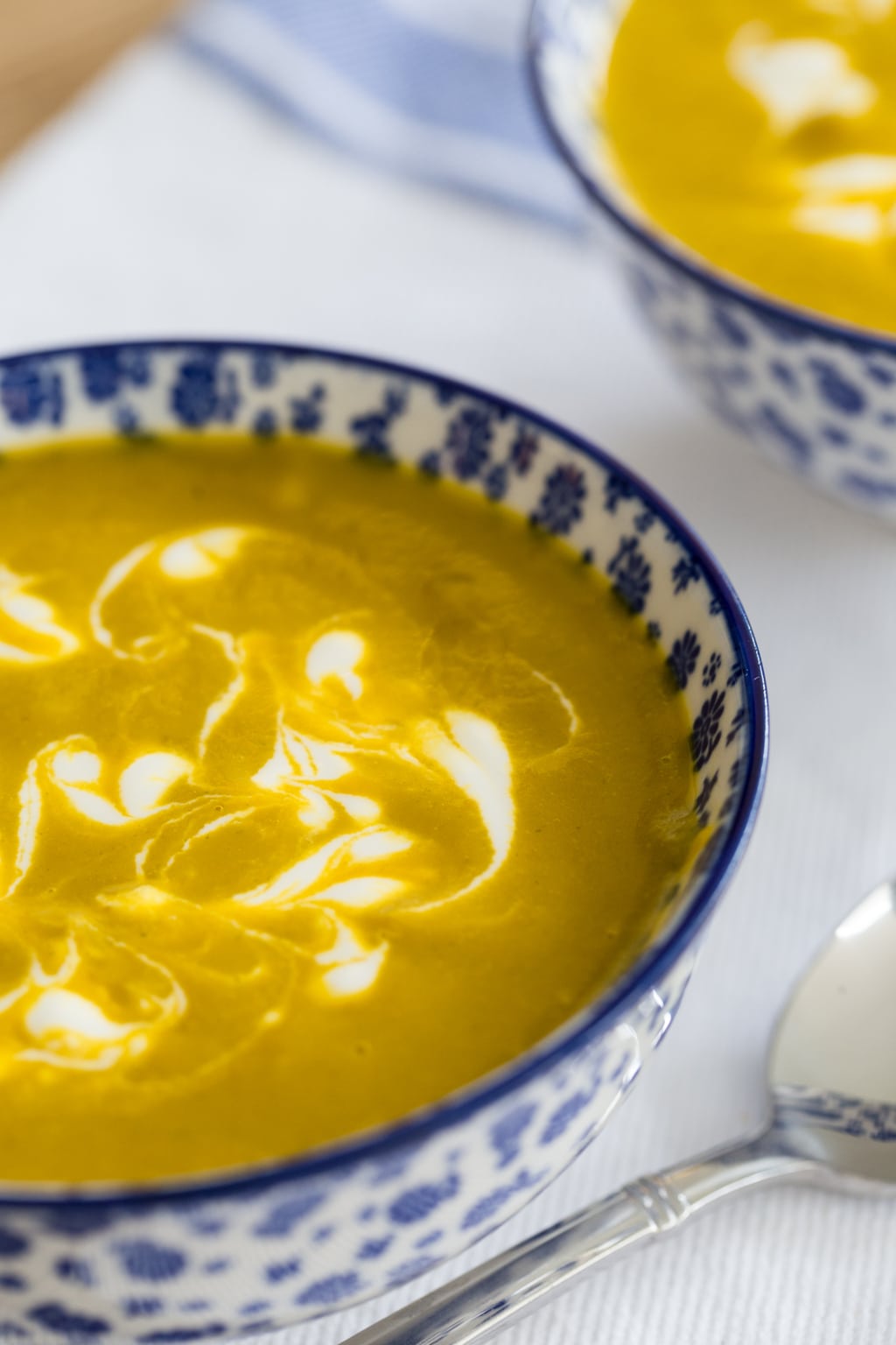Photo of a bowl of Carrot Coriander Soup on a white and blue napkin.