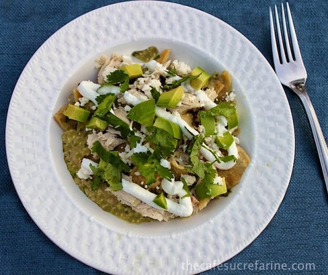 An overhead photo of a white plate of Chicken Chilaquiles Verde on a blue placemat.