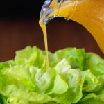 Vertical picture of chili lime dressing poured over fresh butter lettuce