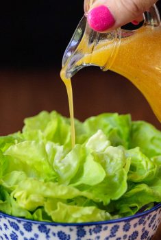Vertical picture of chili lime dressing poured over fresh butter lettuce