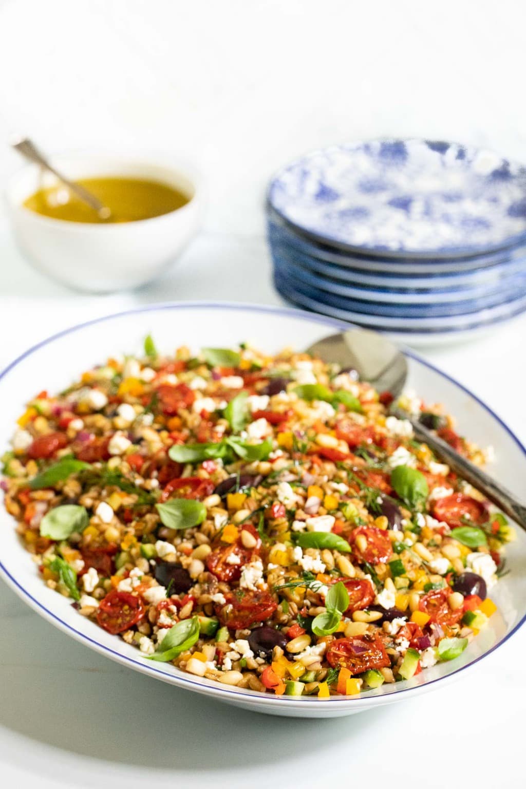 Vertical photo of a Chopped Mediterranean Farro Salad in a blue and white serving platter.