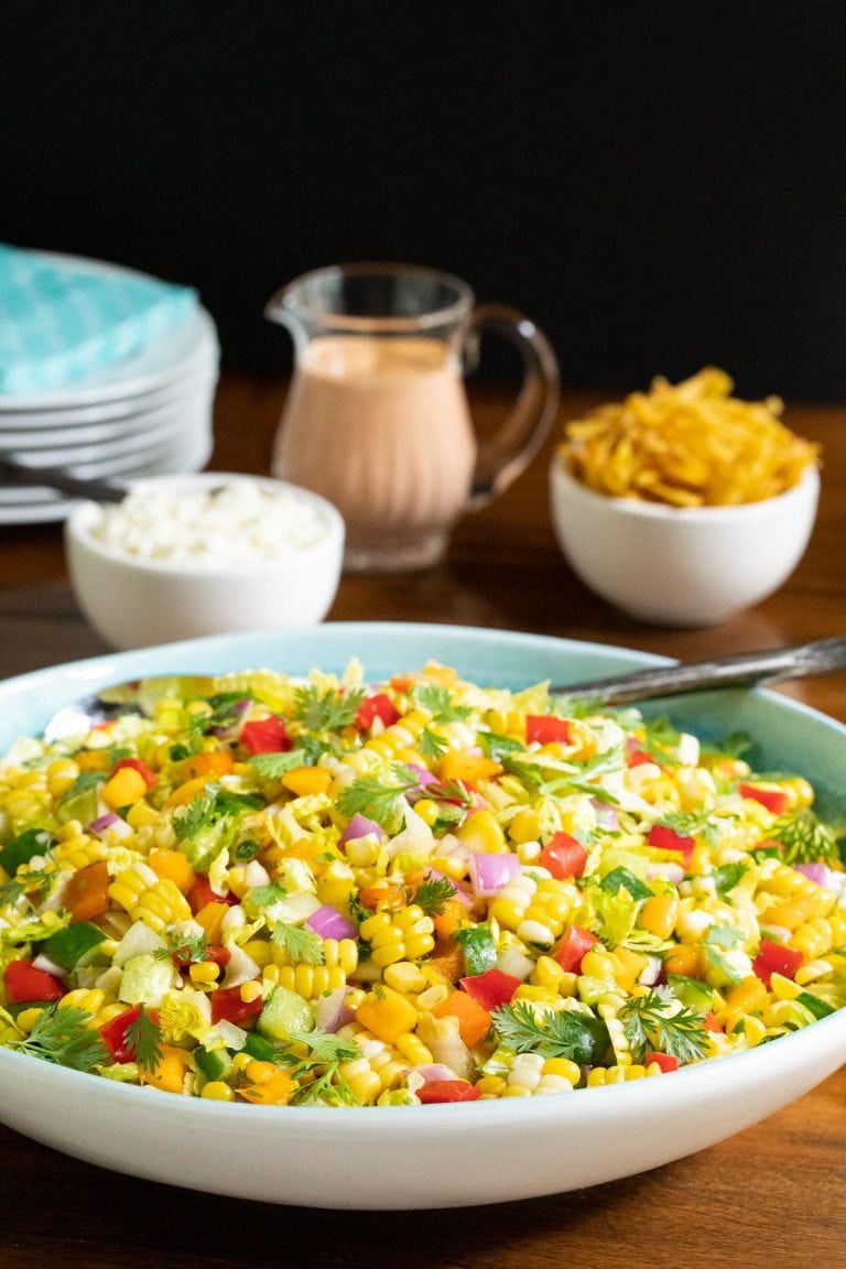 Vertical photo of a Chopped Mexican Street Corn Salad in a white an turquoise serving bowl.