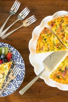 Horizontal overhead photo of a Classic Quiche Lorraine with fresh fruit on the side.