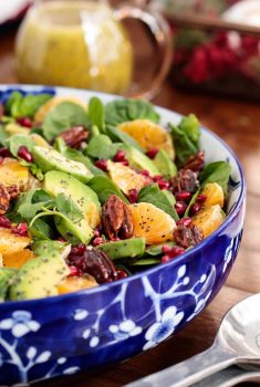 Vertical picture of clementine avocado spinach salad in a blue and white bowl