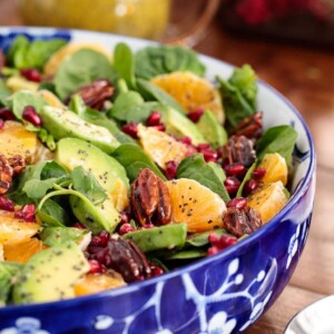 Vertical picture of clementine avocado spinach salad in a blue and white bowl