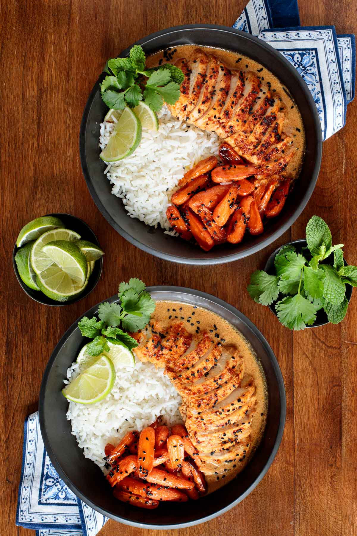 Overhead photo of two individual serving bowls of Coconut Braised Chicken Breasts with white rice and honey ginger charred carrots.