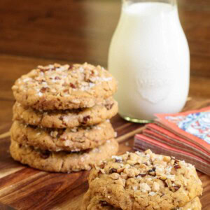 Vertical picture of coconut pecan cookies stacked on a wooden platter with milk