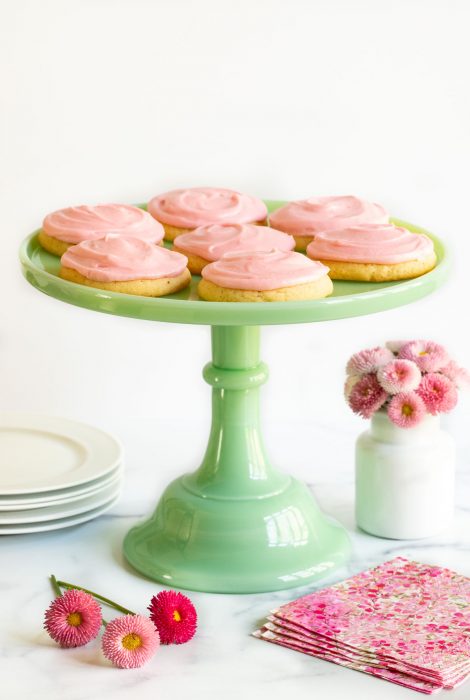 Vertical photo of a batch of Copycat Crumbl Sugar Cookies on a jade colored marble pedestal presentation plate.